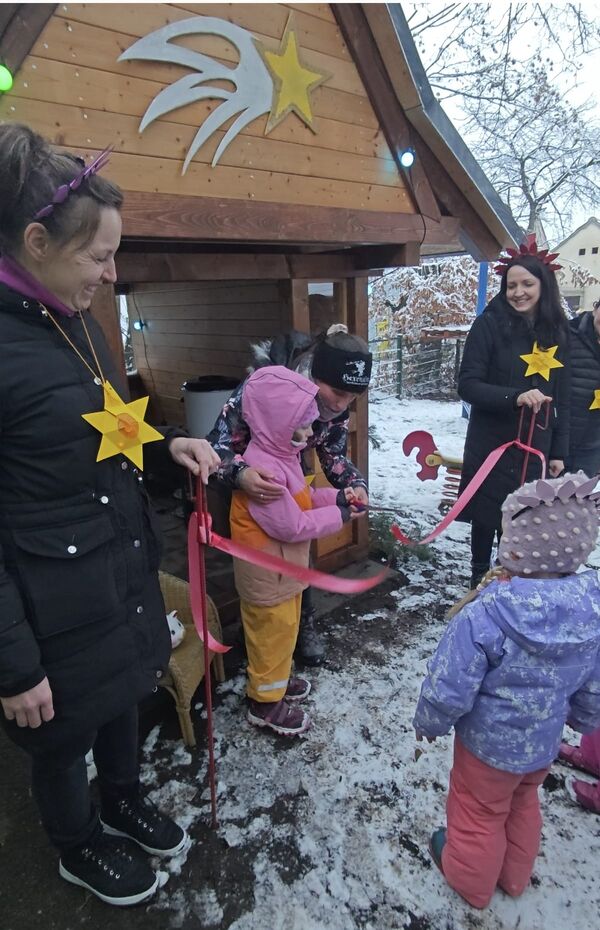 KiTa-Leiterin Manuela Schauer hilft Frieda Kappler beim Durchschneiden des Bandes