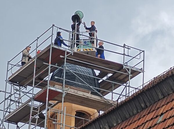Zunächst wurde die kupferne Kugel aufgesetzt. Die Kugel wurde zuvor befüllt mit Informationen für die Nachwelt zu den aktuellen Baumaßnahmen.