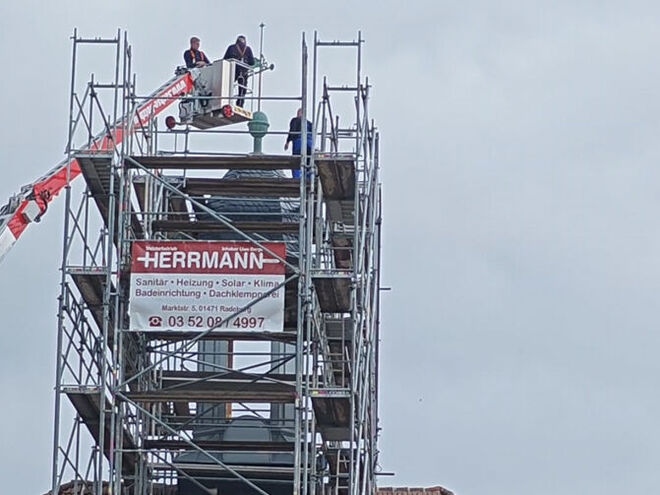 Warum steht das Gerüst noch, obwohl die Turmhaube schon lange auf dem Dach ist? Allein 500 Arbeitsstunden waren in die wettersichere Verkleidung der Holzkonstruktion zu investieren.