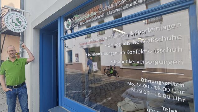 Meister Jens Behrendt verweist auf das Innungszeichen, das seit einigen Tagen werbesatzungskonform als Ausleger den Weg zu seinem Laden weist.