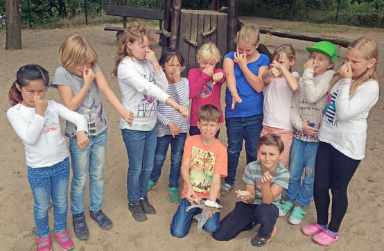Die Kinder halten sich die Nase zu und präsentieren Unrat von ihrem Spielplatz.